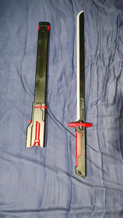 Katana preta e vermelha ao lado da bainha, recém-desembalada