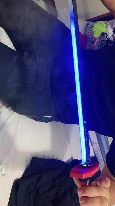 Katana com lâmina LED azul acesa em um quarto